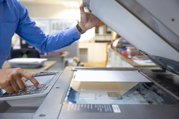 Businessmen press button on the panel of photocopier or printer for printout, scanning, exrox documents papers at office workplace. Contex